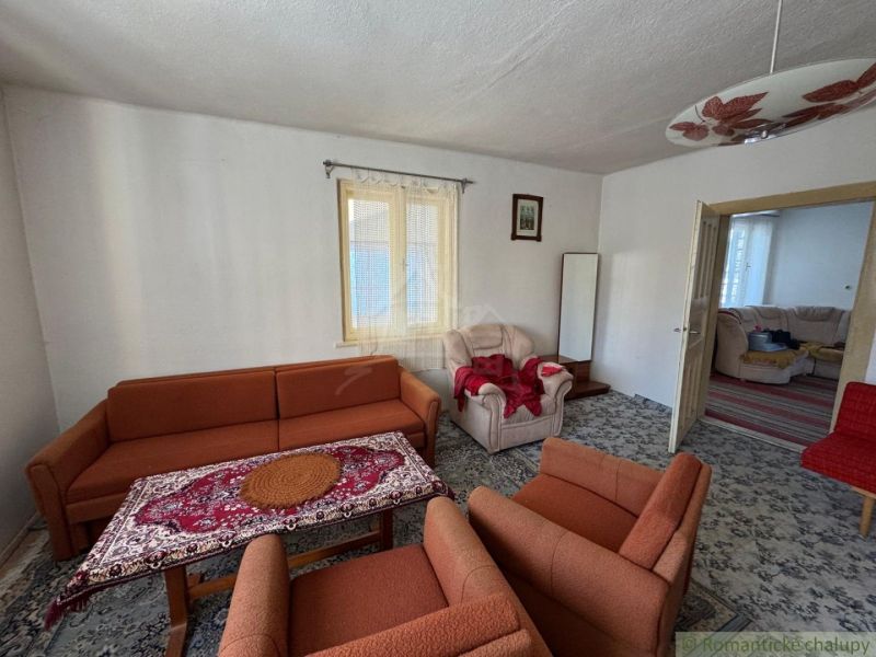 Living room in a family house with an orange sofa and a patterned carpet.