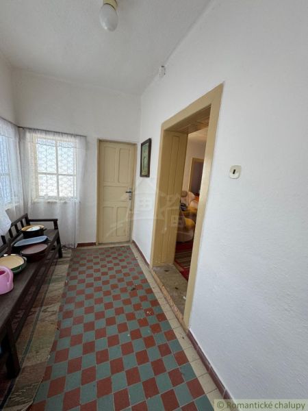 Hallway in a family house with a tiled floor, white walls, and simple furnishings.