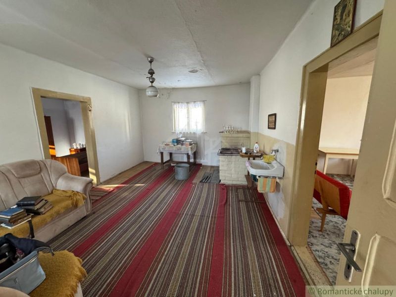 Interior of a family house with older furniture, a striped pattern carpet, and a sofa.