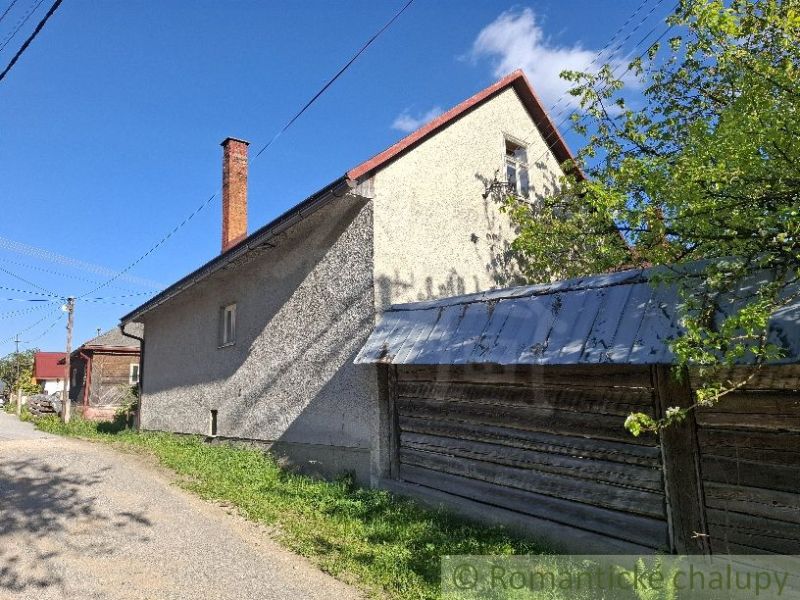 A family house in Šumiac with a metal roof, adjacent to green nature and a road.