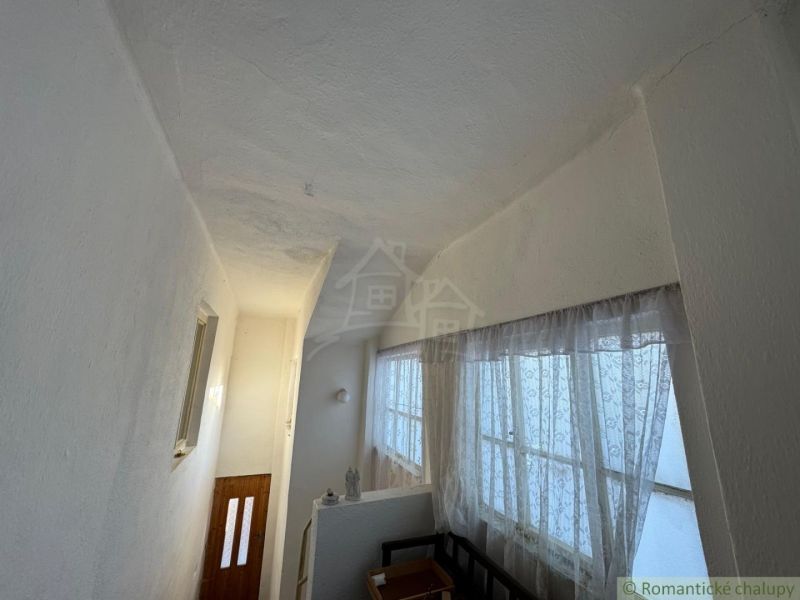 The interior of a family house with a narrow hallway and curtain windows.