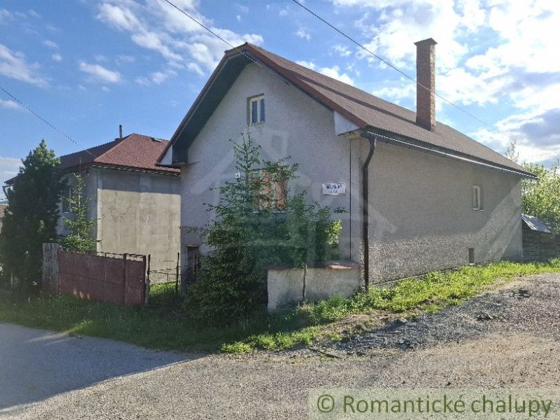 A family house in Šumiac with a metal roof and a garden by the road.