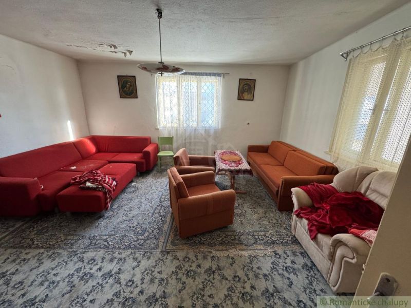 Living room in a family house with red and orange sofas and a carpet.