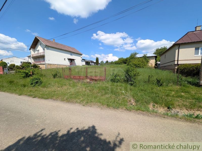 A house surrounded by greenery in Karna, bordered by a fence, ideal for residential land.