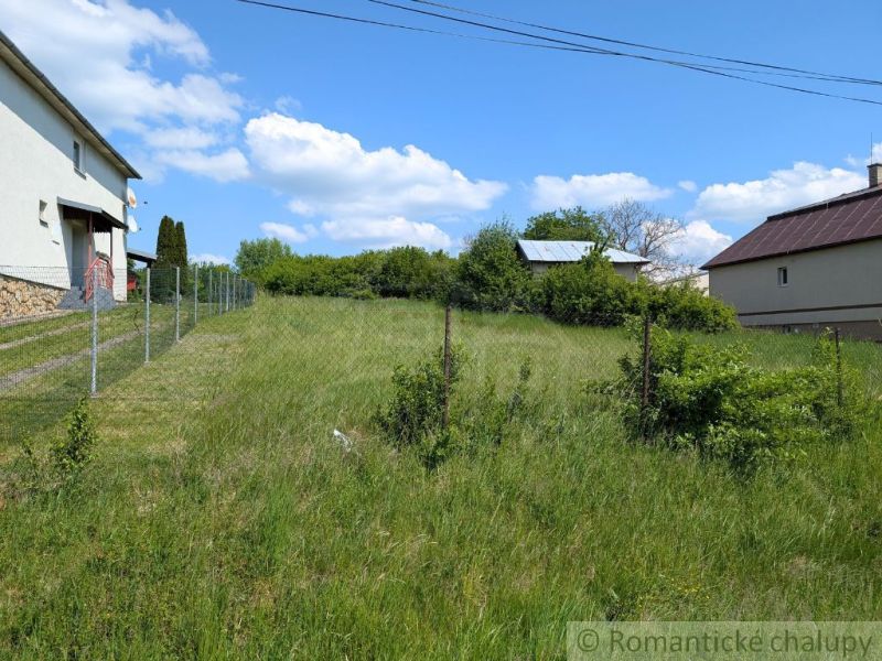 Plots - housing in Karna, grassy area with fencing and adjacent buildings.