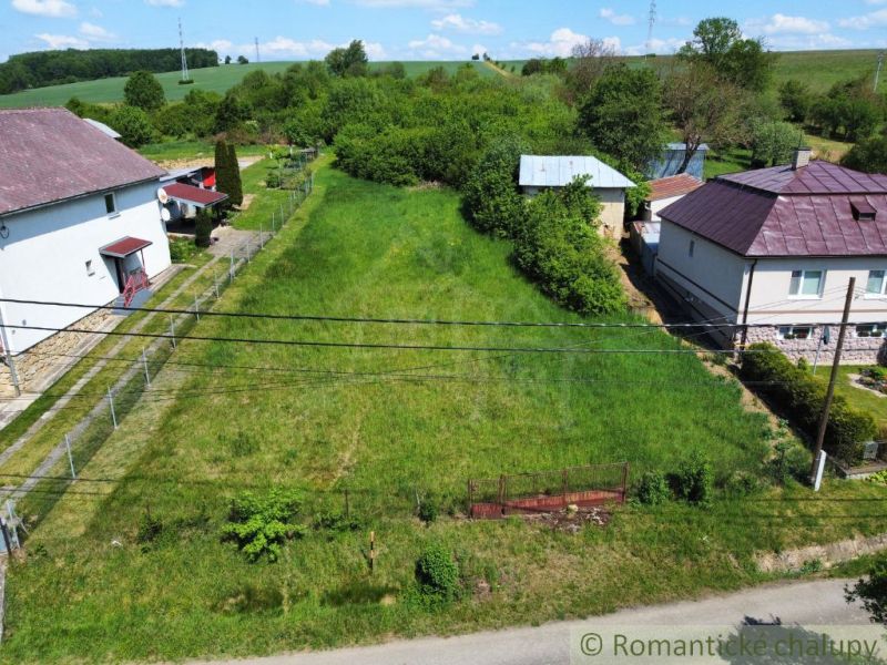 A plot for residential use in Karna, bordered by neighboring houses and greenery.