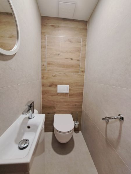 Bathroom in a 2-room apartment with wood-patterned flooring and a wall-mounted toilet.