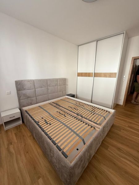 A bedroom with a bed, a wardrobe, and a wooden decor floor in a two-room apartment.