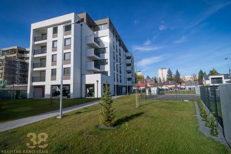 An apartment building in Poprad with a green lawn and neighboring buildings in the background.