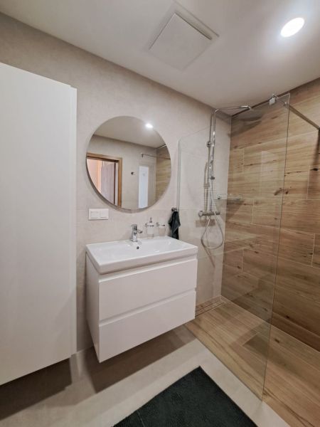 Bathroom in a 2-room apartment with a sink, shower corner, and floor with wood decor.