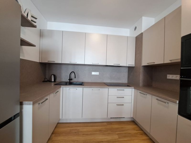 A kitchen in a 2-room apartment with a wooden decor floor and elegant furniture.