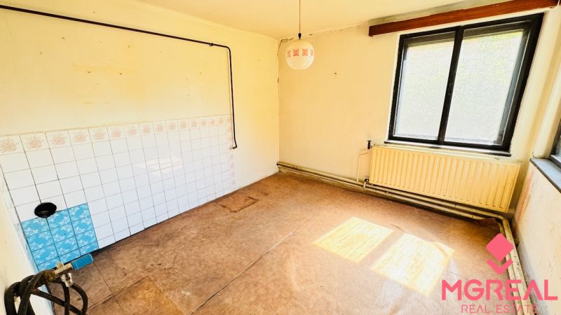 Unfurnished room with a window, radiator, and wooden decor flooring in a family house.