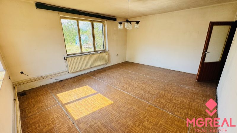A room with a wooden floor design, a large window, and a radiator in a family house.
