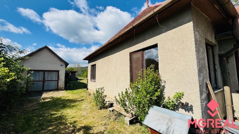 A family house in Pažiť with a garden and a separate garage under the blue sky.