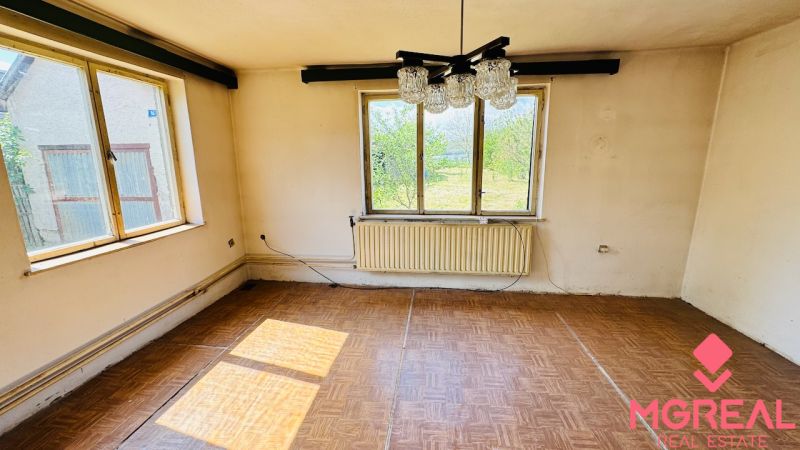 A room in a family house with a wooden decor floor and large windows.