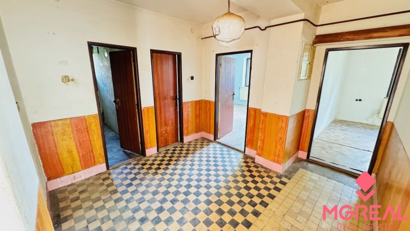 A hallway in a family house with tiled flooring and wooden decor on the walls.