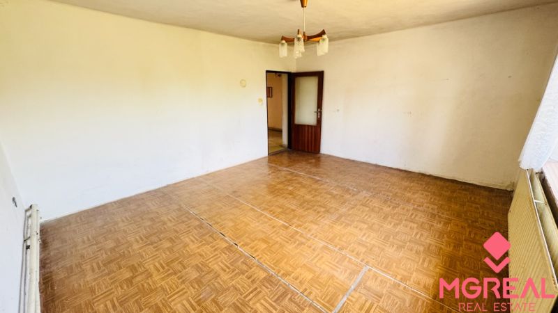 A room in a family house with a wooden decor floor and a chandelier.