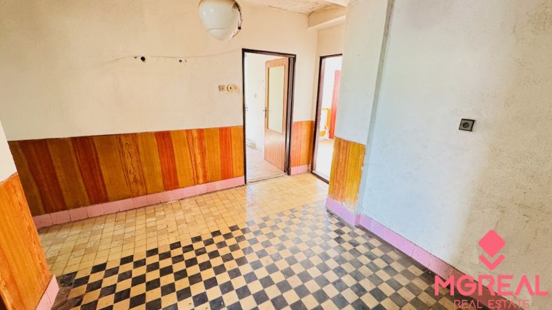 The interior of a family house with a tiled floor and wood decor on the walls.