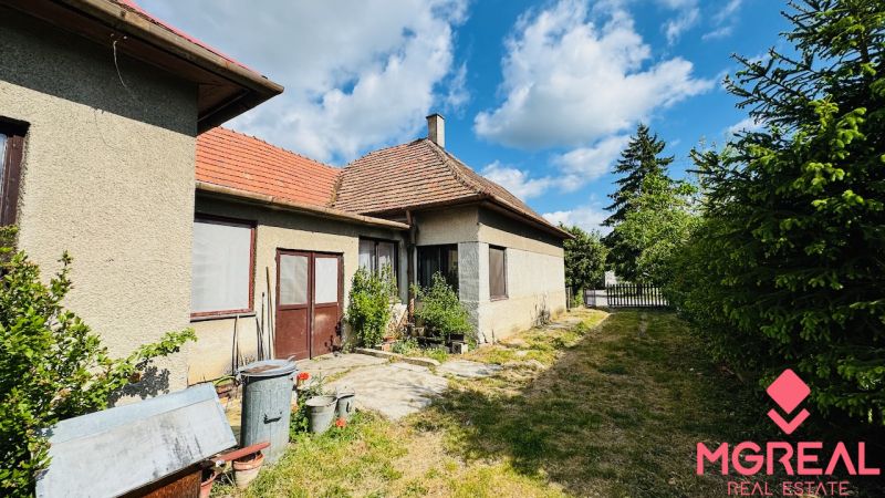 A family house in Pažiť with two entrances, windows with screens, next to a narrow garden.