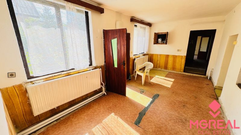 The interior of a family house with open doors, plastic chairs, and large windows.