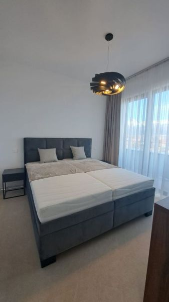 Bedroom in a 2-room apartment with a bed, nightstand, and curtains.