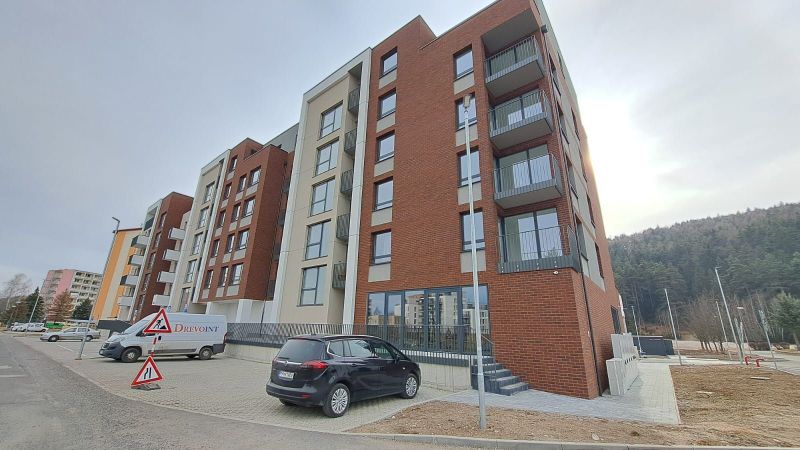 Apartment building on Jilemnického Street in Svit, with a parking lot and surrounding green landscape.