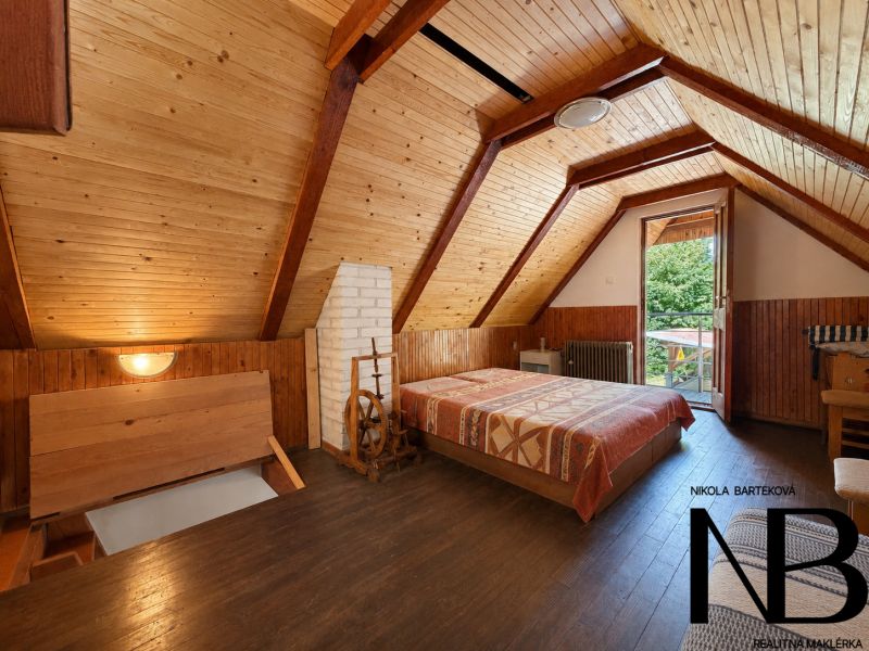 Interior of a cabin with wooden paneling and a floor with a wooden decor, visible bed and entrance.