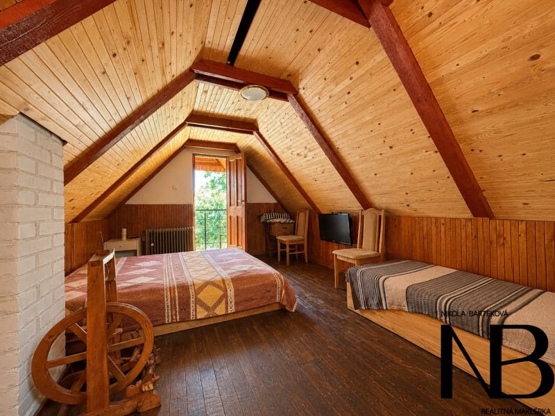 Attic room in a cottage with wooden decor and a bed.