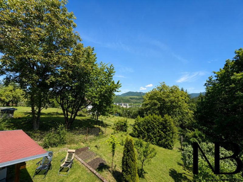 The garden of the cottage at Klučina in Považská Bystrica with lush greenery and chairs.