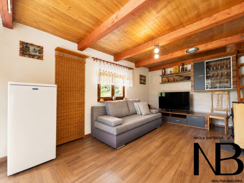 Living room of the cottage with a wooden decor floor, comfortable sofa, television, and cabinets.