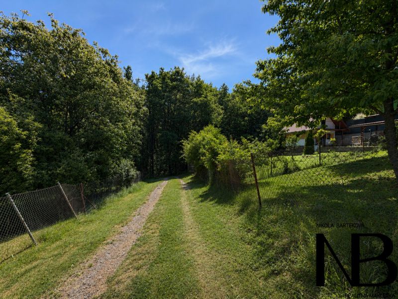 A cottage on Klučina Street in Považská Bystrica surrounded by greenery and a blue sky.