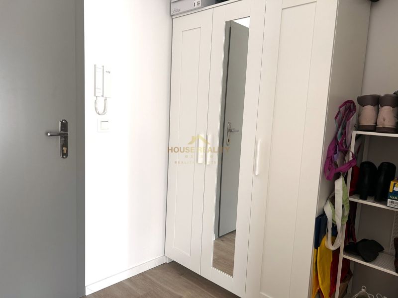 Built-in wardrobe with white doors and a mirror in a studio apartment.