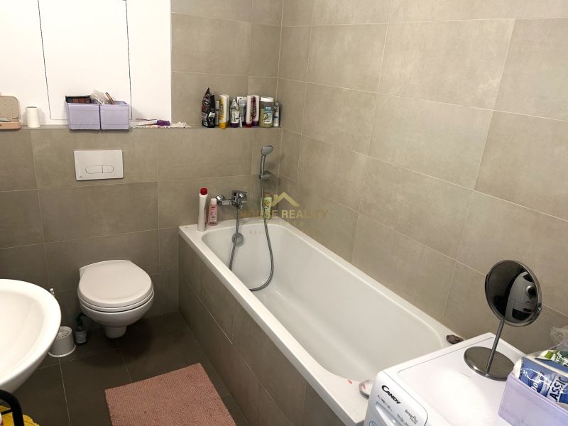 Bathroom with a bathtub, toilet, and washing machine in a studio apartment.