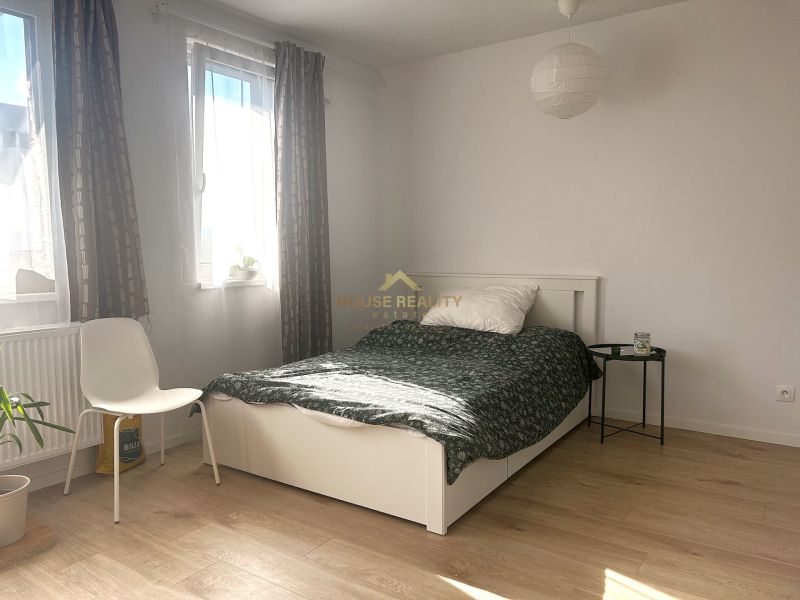 A bright room in a one-room apartment with a bed and a wooden decor floor.