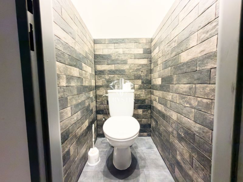 Toilet in a family house with brick wall cladding and gray flooring.