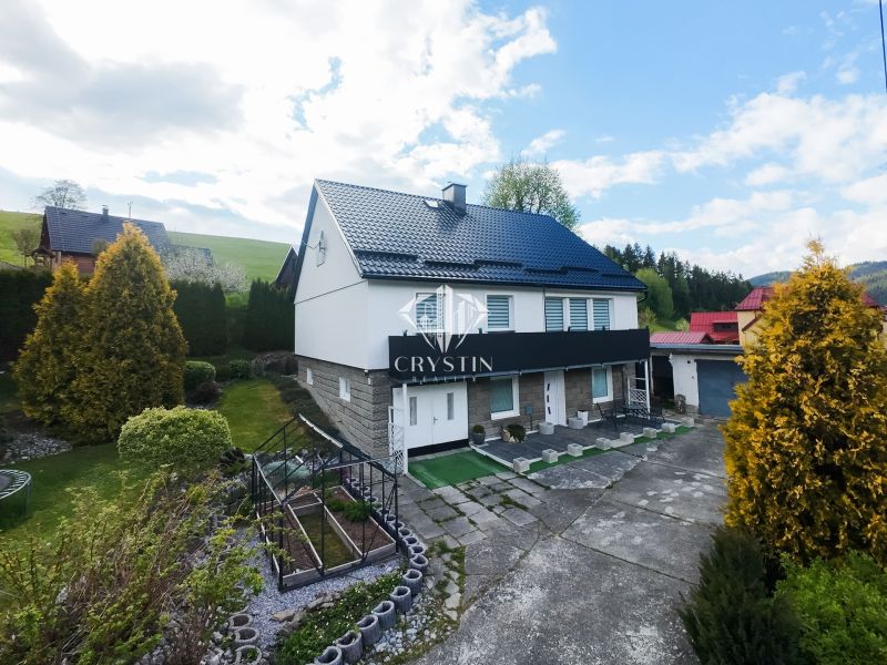 A family house in Makov surrounded by a well-maintained garden with a greenhouse and paved paths.
