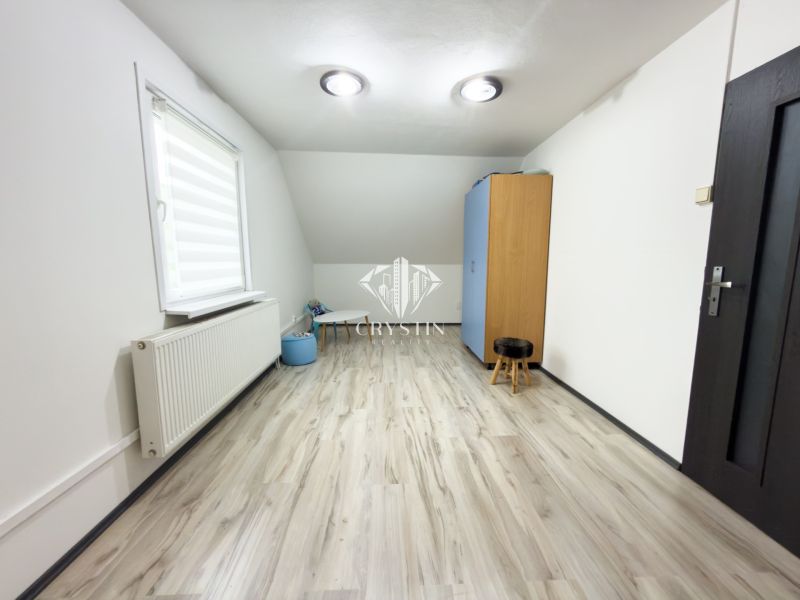 A room in a family house with a floor featuring a wooden decor and simple furniture.
