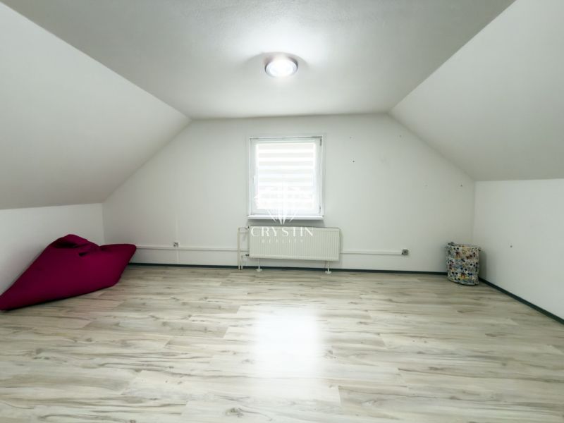 Attic room in a family house with a floor featuring a wooden decor and white walls.