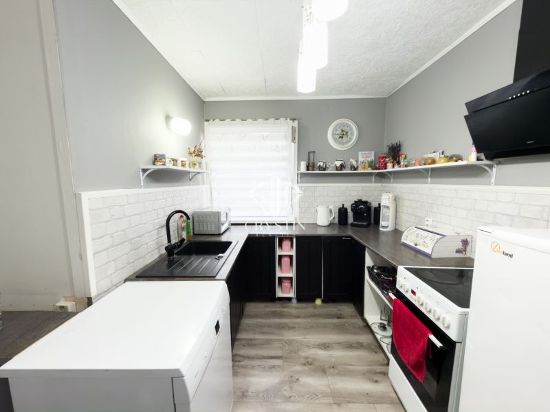 A kitchen in a family house with a wooden decor floor and gray walls.