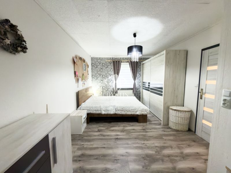 A bedroom in a family house with a wooden decor floor and tasteful furnishings.