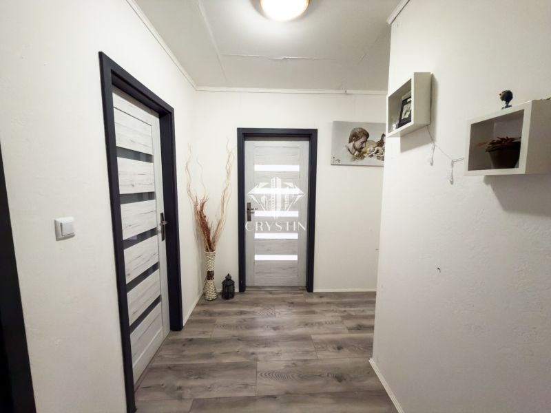 A hallway in a family house with a wooden decor floor and decorative shelves.