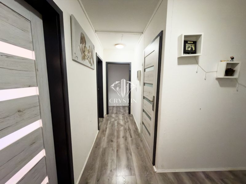 A hallway in a family house with a wooden decor floor and decorations on the walls.