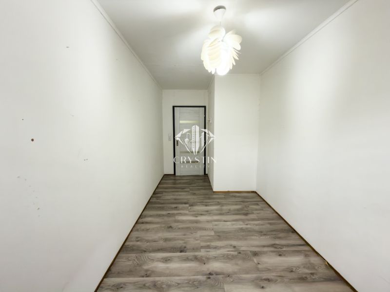A narrow hallway in a family house with a wooden decor floor and a white ceiling.