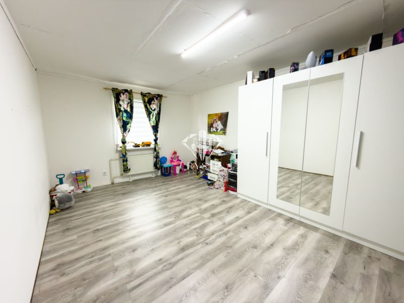 Children's room with a white wardrobe, window, and wooden decor flooring in a family house.