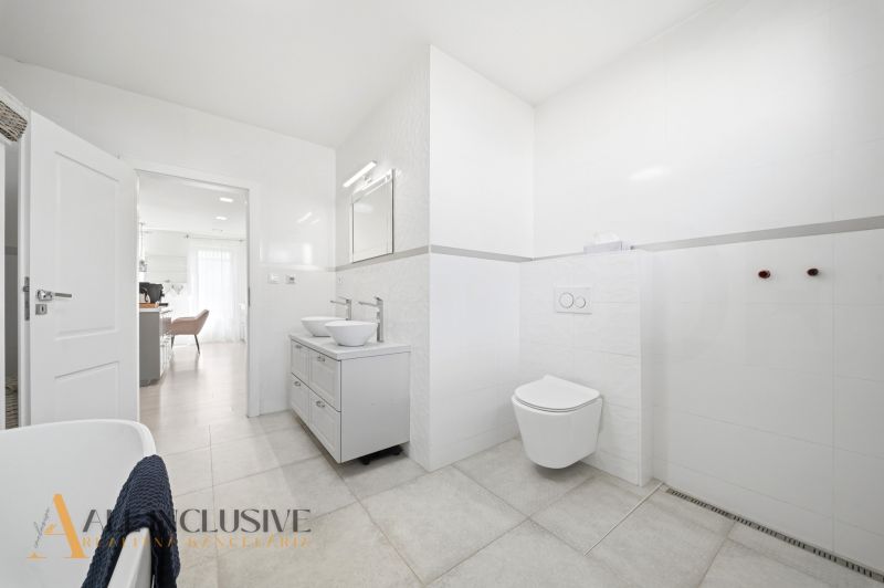 A bathroom with a shower, double sink, and toilet in a family house.