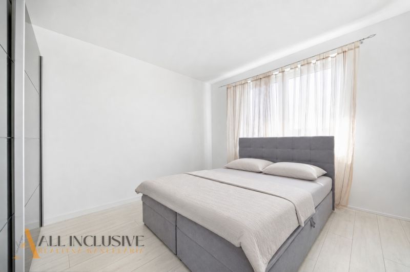 Bright bedroom with a bed, wardrobe, and curtains in a family house.