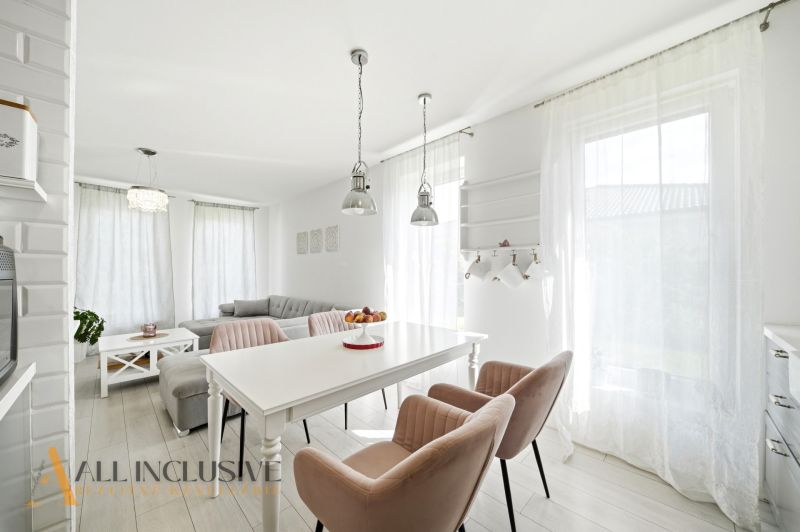 Interior of a family house with comfortable chairs, a dining table, and a sofa under large windows.