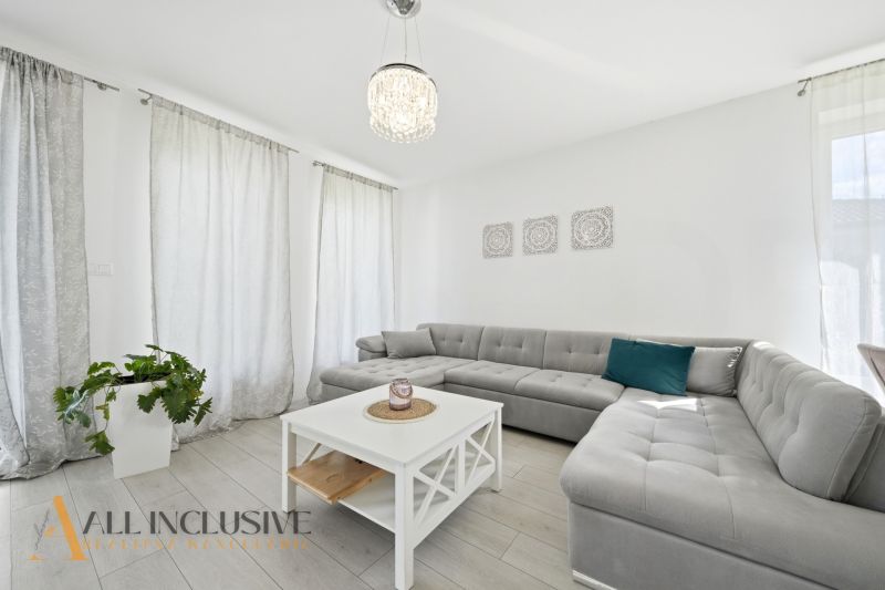 Bright living space with a corner sofa and wood-patterned flooring in a family house.