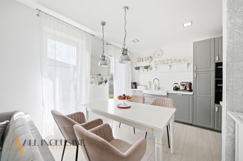 A kitchen in a family house with white furniture and wooden floor decor.