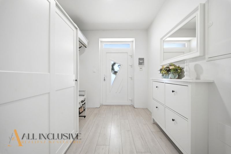 The entrance hall of a family house with white furniture and a wooden decor floor.